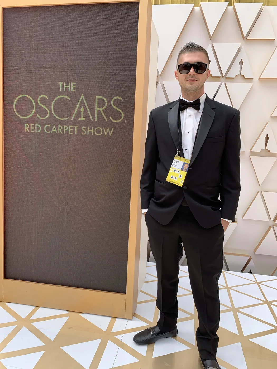 Zak Holley in a tuxedo at the Oscars Red Carpet Show, wearing his Verizon tech manager credential
