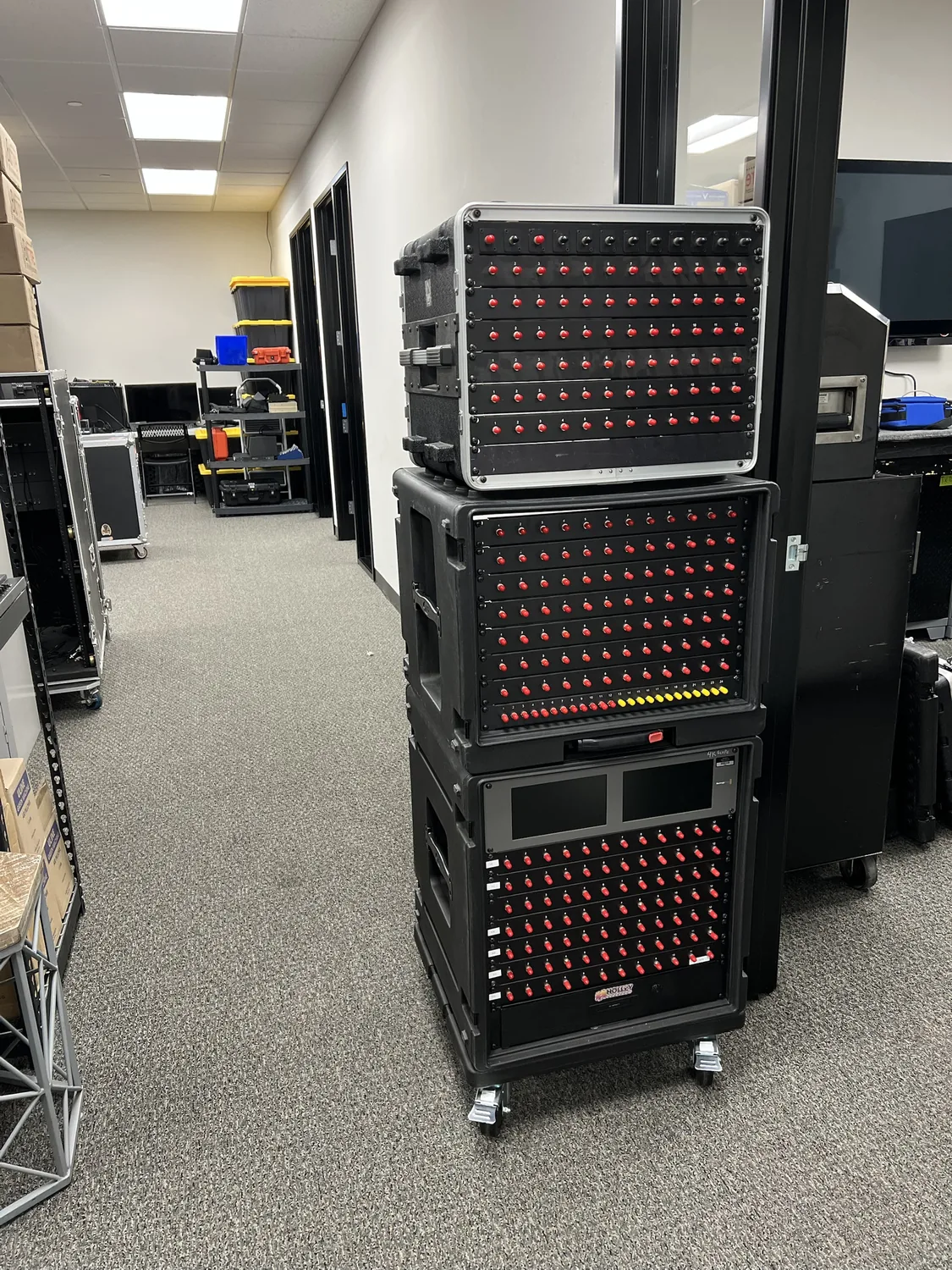 Three stacked road cases of fiber and SDI patch panels in the shop